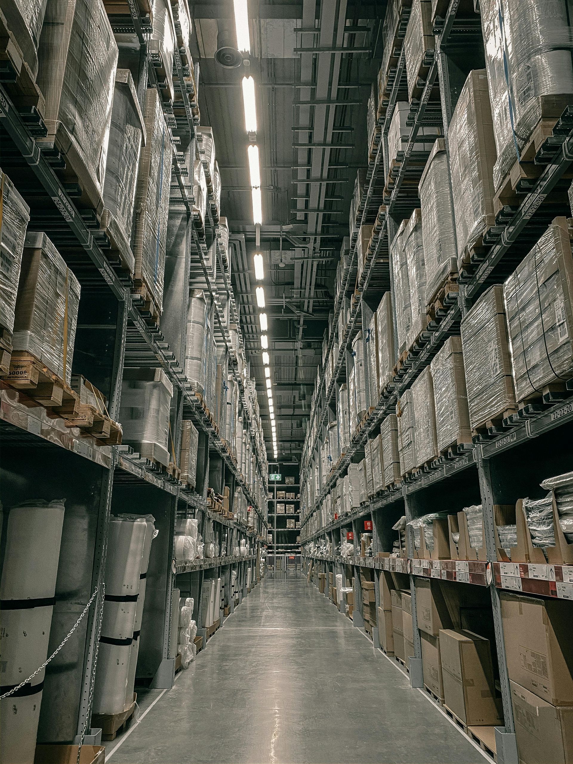 Tall warehouse aisle with stacked pallets and boxes on both sides