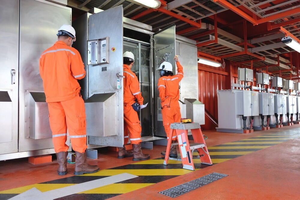 Group of Men in Orange Jumpsuits Are Working on a Machine — Proserpine Electrical Services in Proserpine, QLD