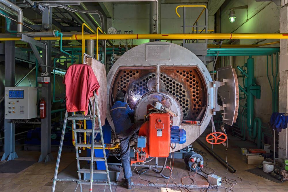 Man is Welding a Large Boiler in a Factory — Proserpine Electrical Services in Whitsundays, QLD