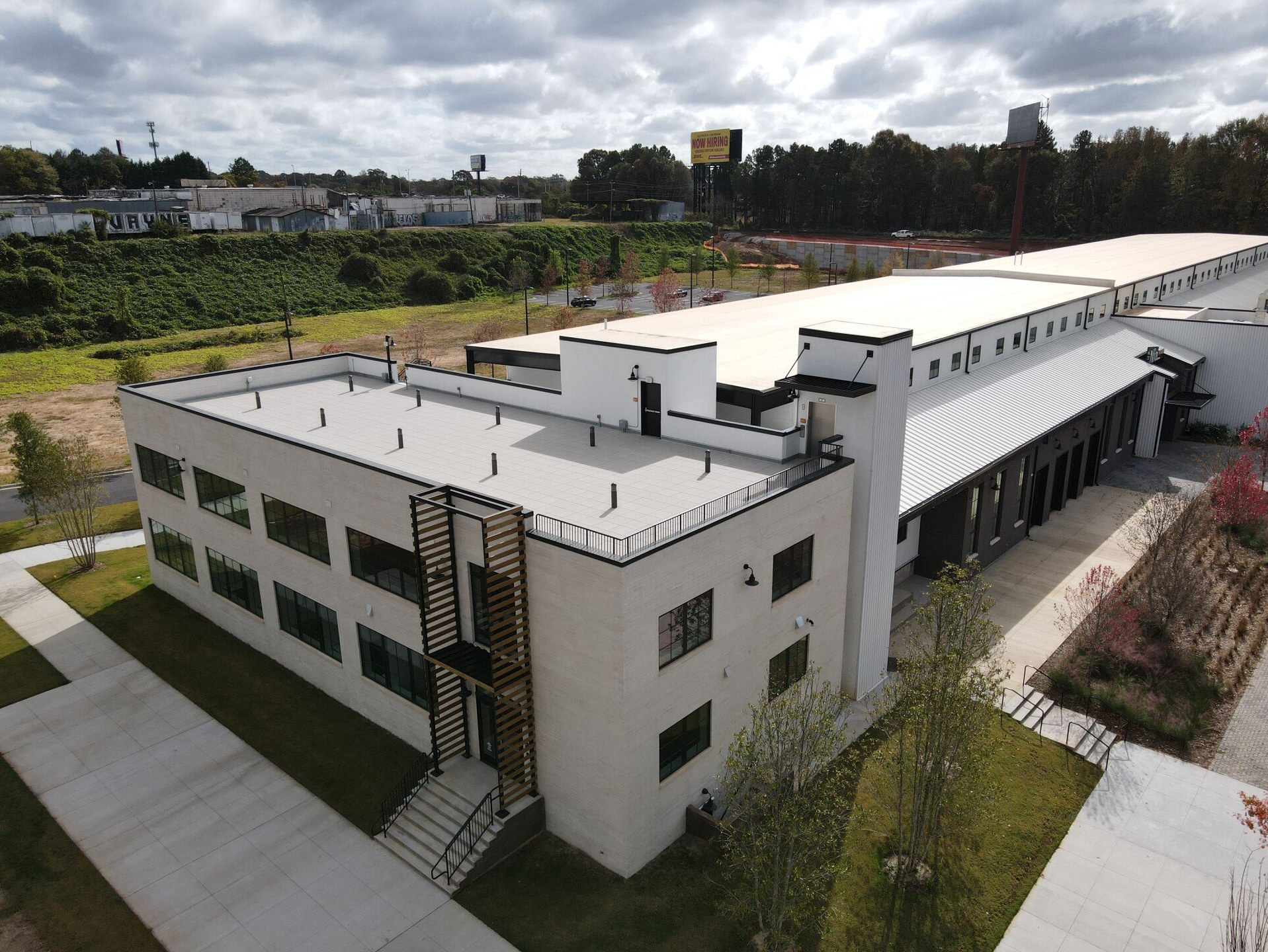 Exterior view of a modern white building with a flat roof, green lawn, and walkway. 