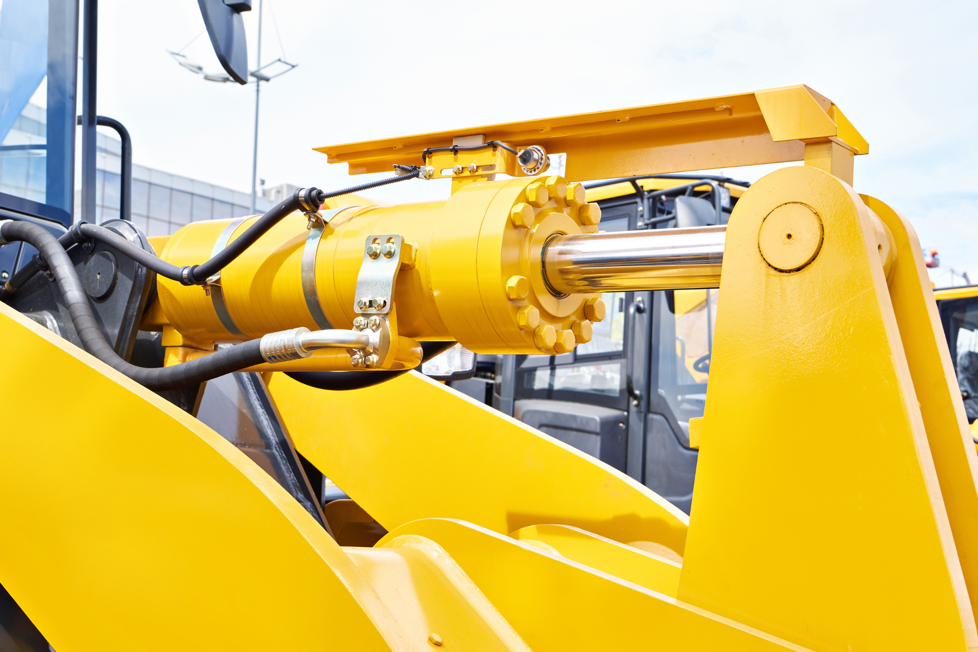Yellow hydraulic excavator arm and cylinder at a construction site