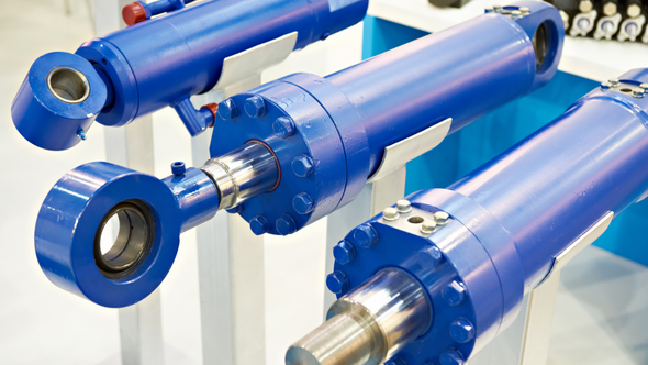 Blue hydraulic cylinders with chrome rods displayed on a white stand in a showroom