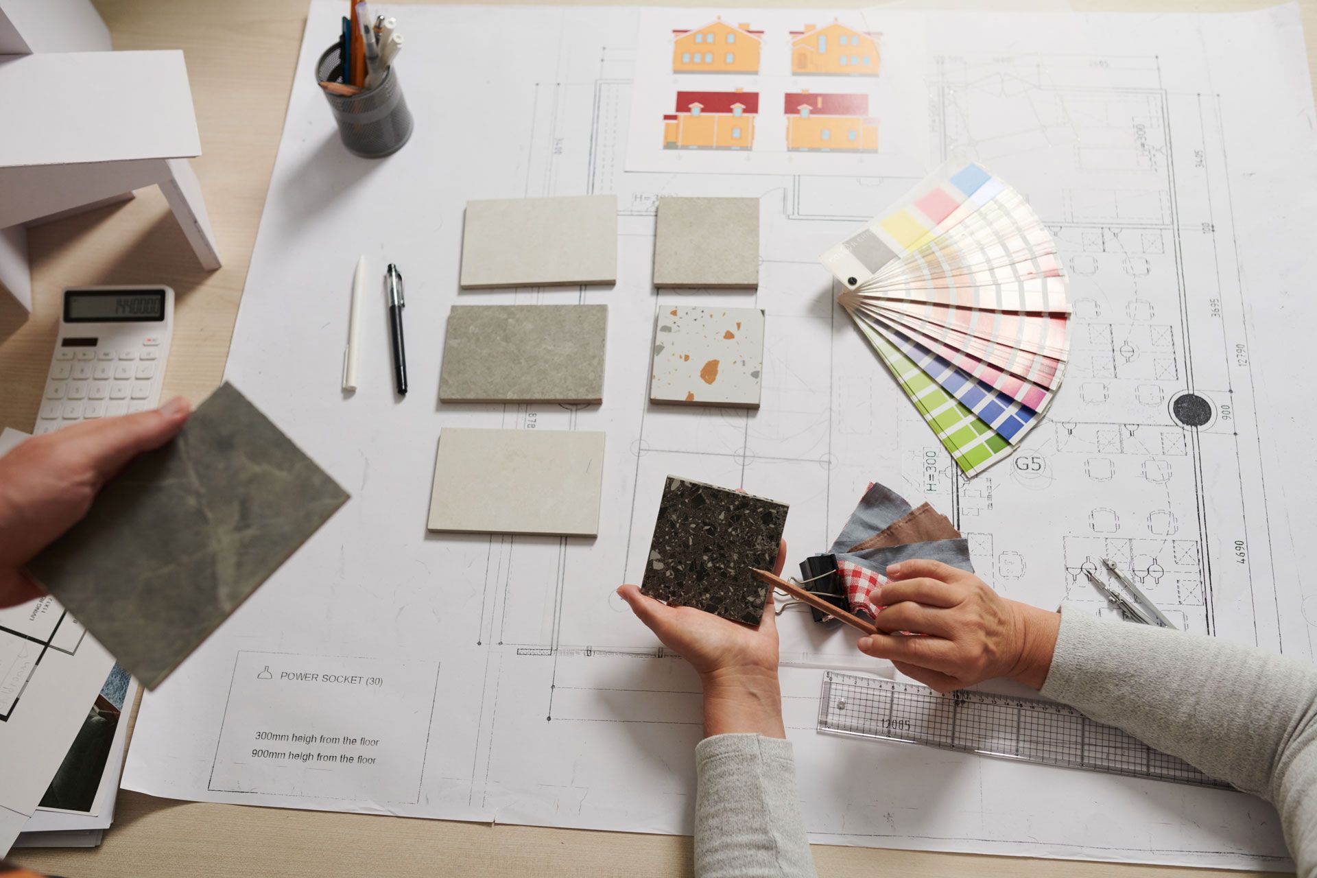 Two people reviewing fabric swatches and color samples on a design workspace
