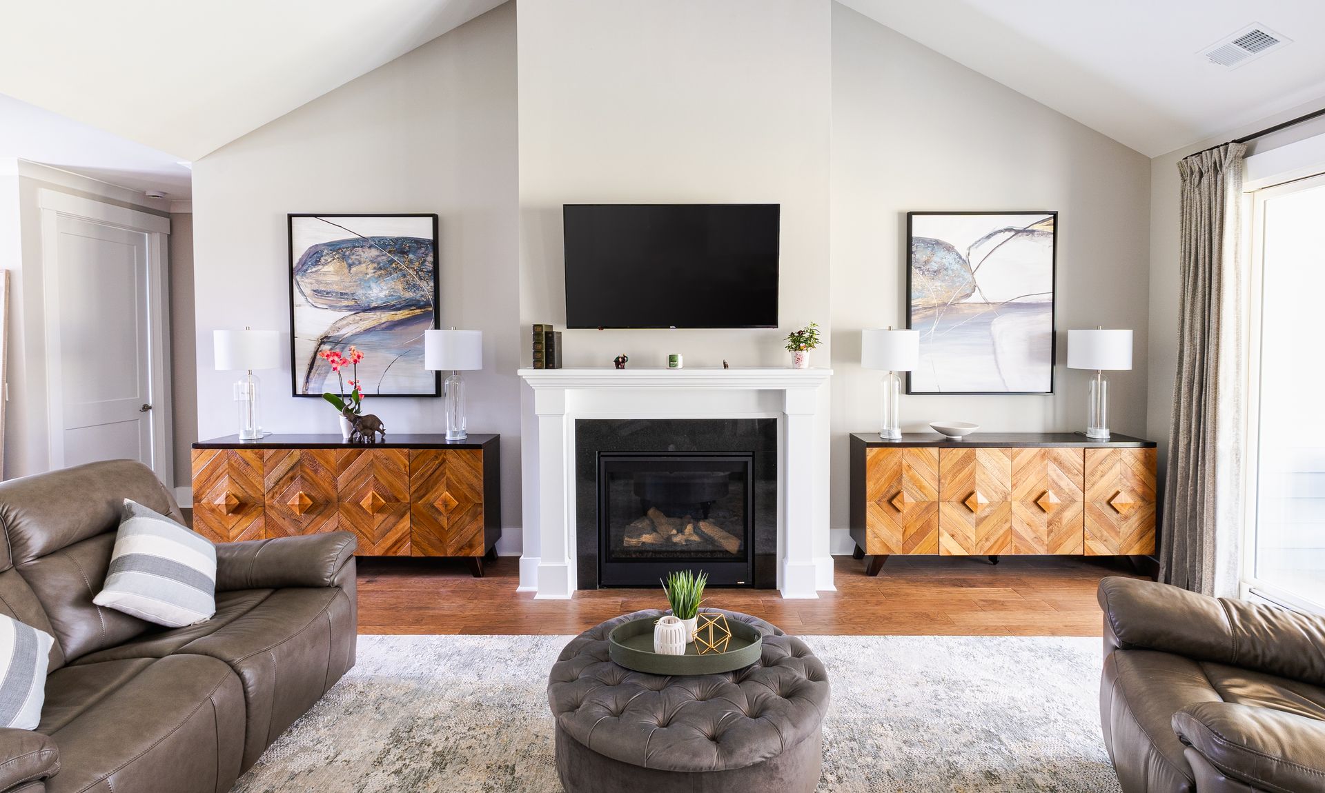Living room with fireplace, TV, two cabinets, sofas, and large rug.