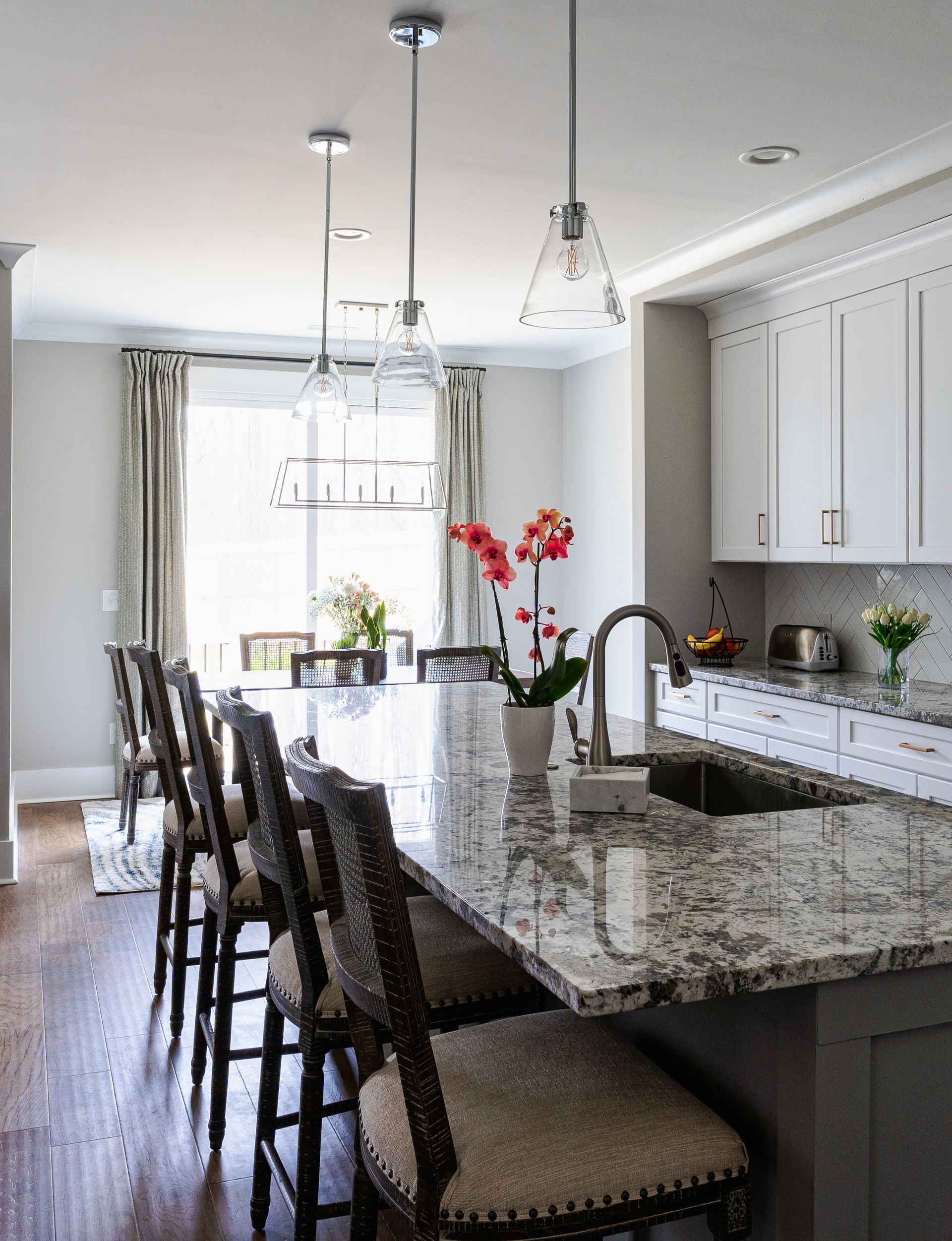 Kitchen with island, stools, and overhead lighting, with a window in the background.