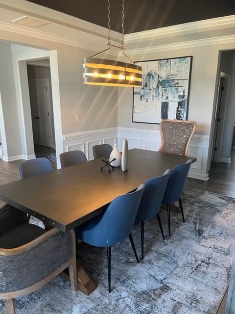 Dining room with a dark table, blue chairs, and artwork, with a light fixture overhead.