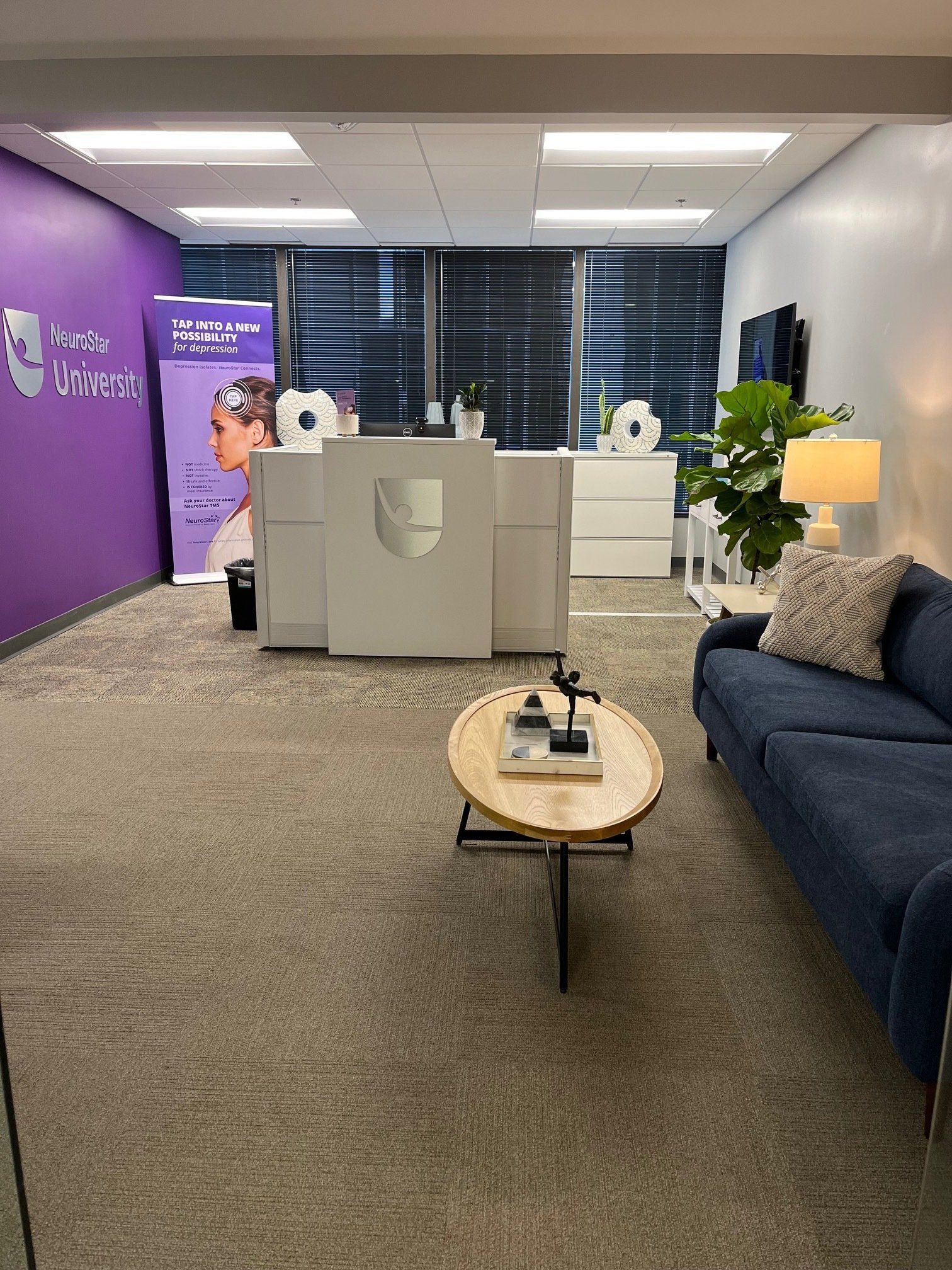 An office with medical equipment, a blue couch, and a round coffee table.