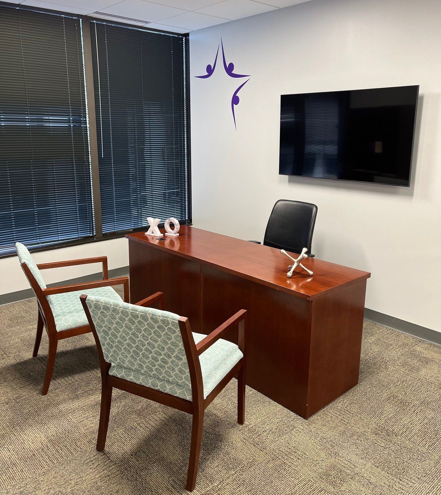 Office with a desk, chairs, window with blinds, TV, and decorative wall art.
