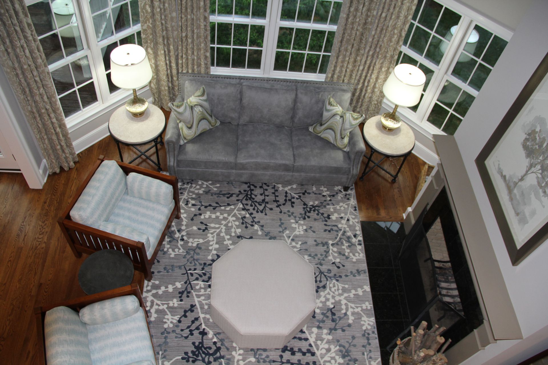 Living room with gray sofa, two chairs, rug, round tables, fireplace.
