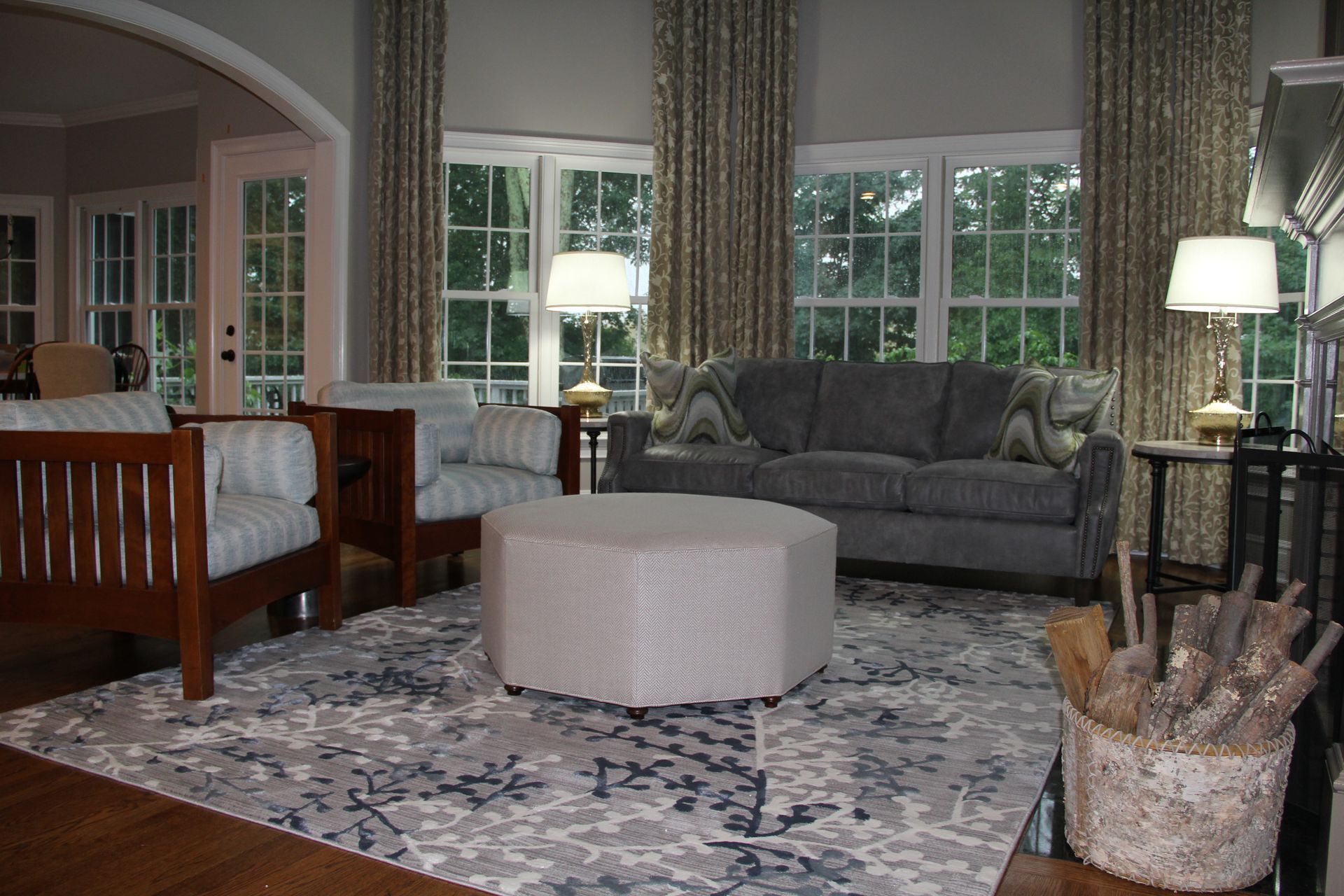 Living room with gray sofa, chairs, patterned rug, and a large ottoman.