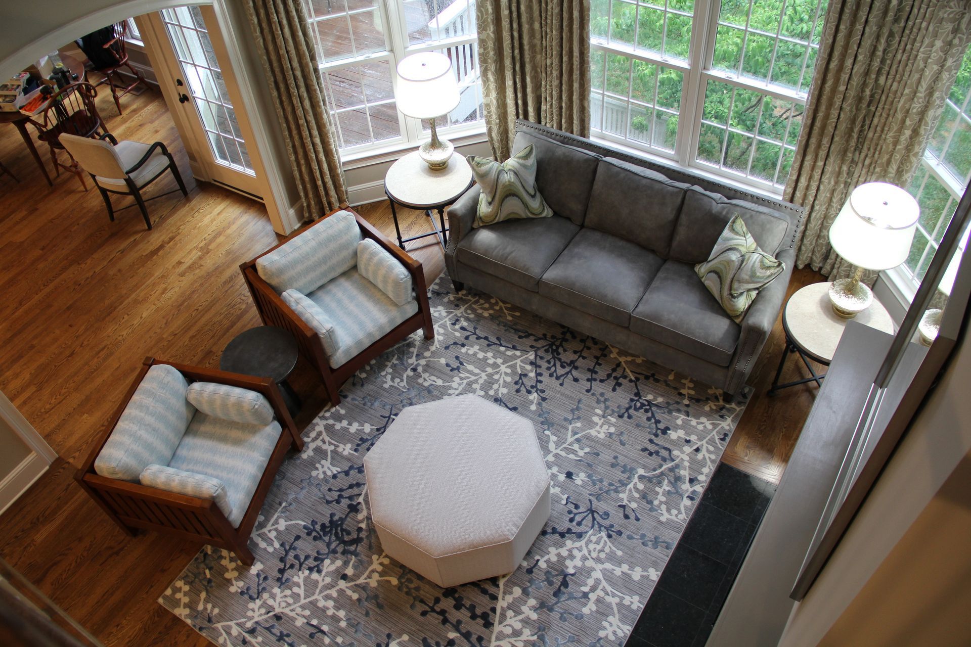 A living room with gray sofa, two armchairs, and patterned rug, viewed from above.