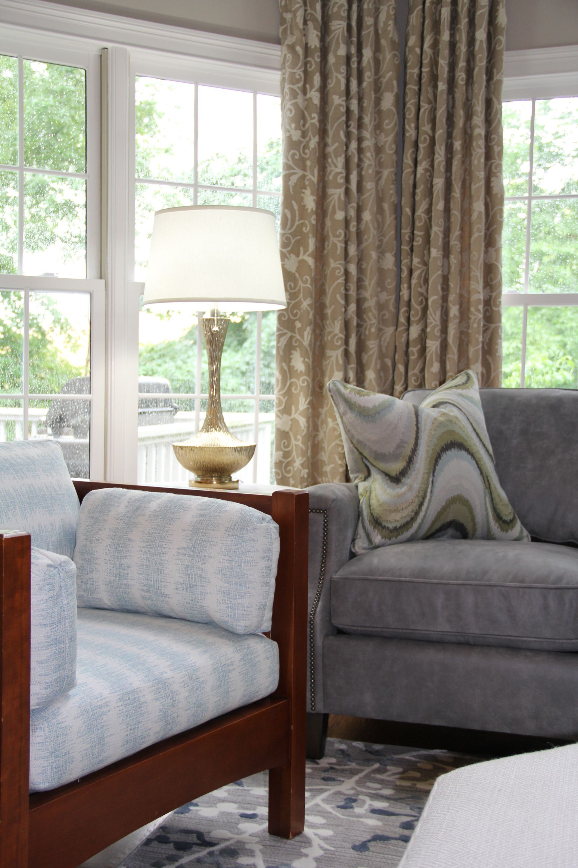 Living room with gray sofa, patterned curtains, and light blue arm chair.