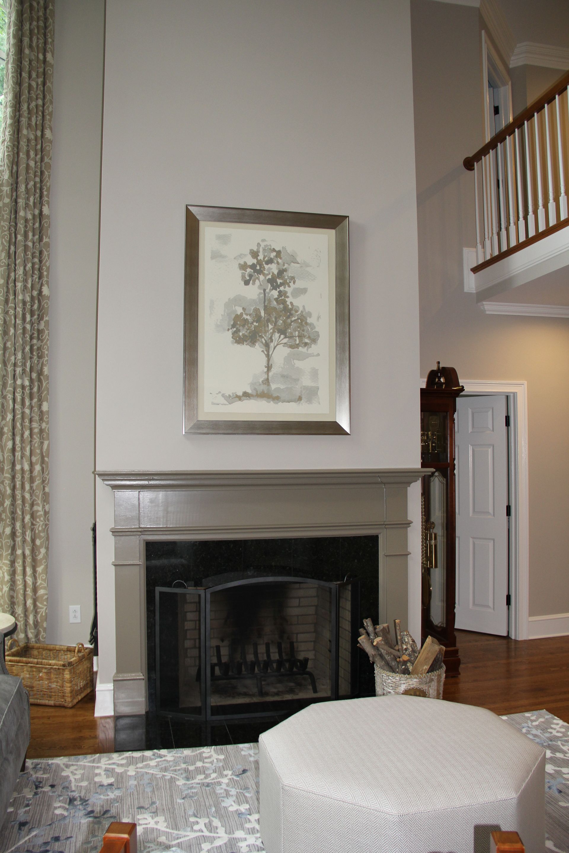 Fireplace with a painting of a tree above it in a light gray room.