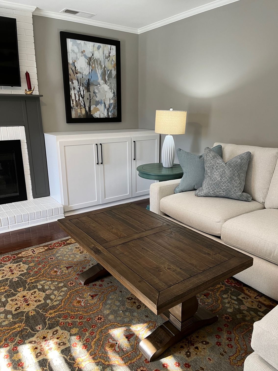 Living room with a coffee table, sofa, fireplace, built-in cabinets, art, and a lamp.
