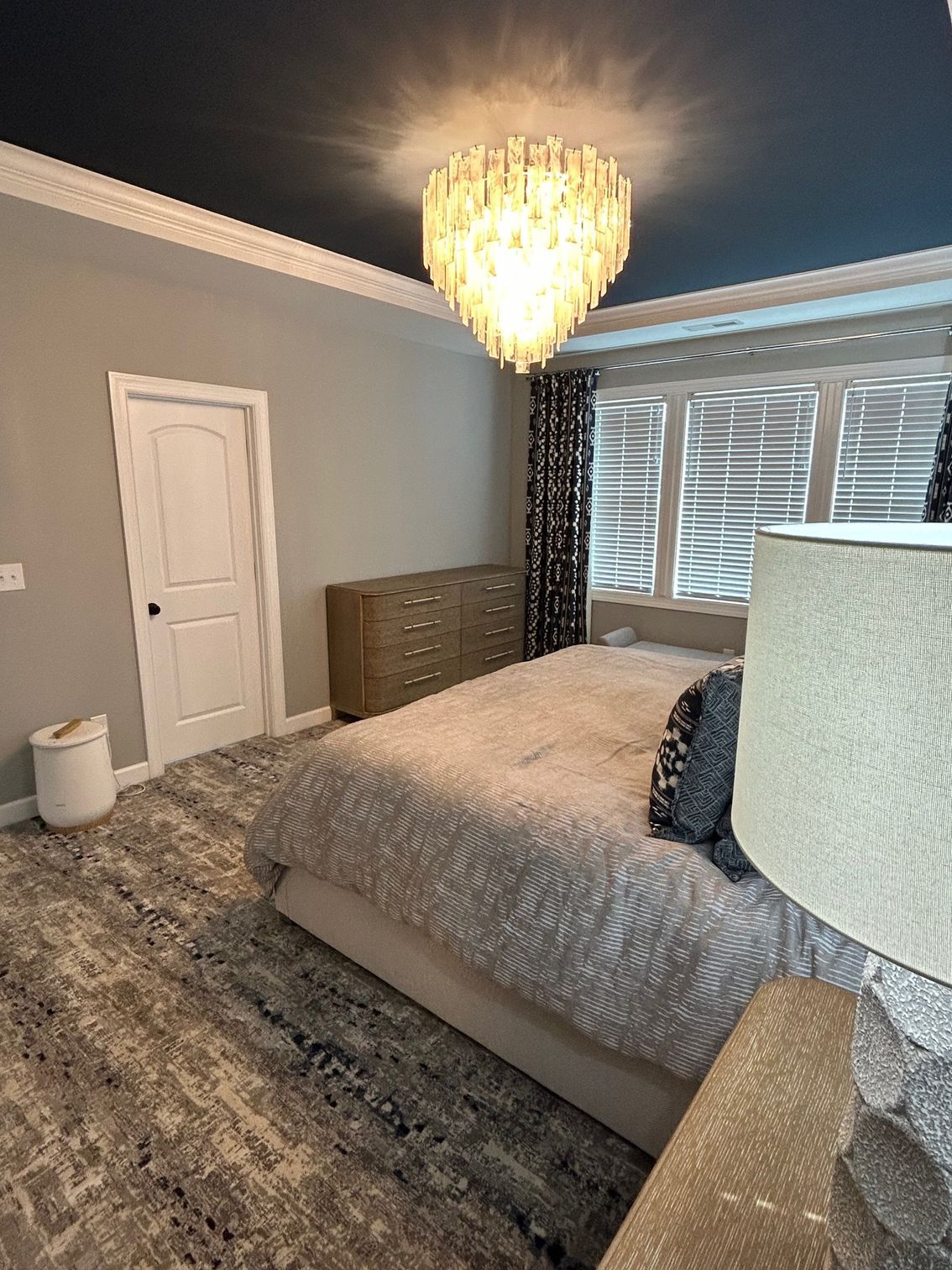 Bedroom with gray walls, blue ceiling, chandelier, bed, dresser, and window.