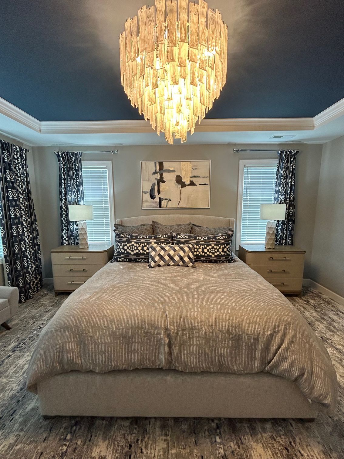 Bedroom with a large bed, nightstands, and a dramatic chandelier.