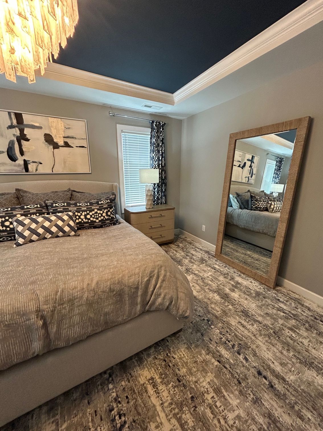 Bedroom with gray walls, bed, rug, mirror, and a blue ceiling with white crown molding.