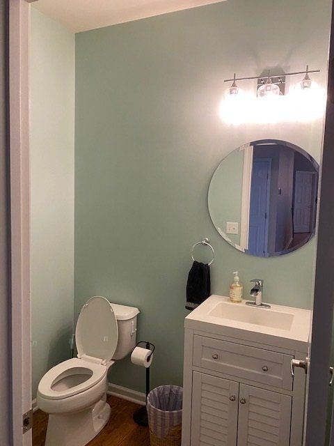 Small bathroom with a toilet, sink, mirror, and light fixture; walls are painted aqua.