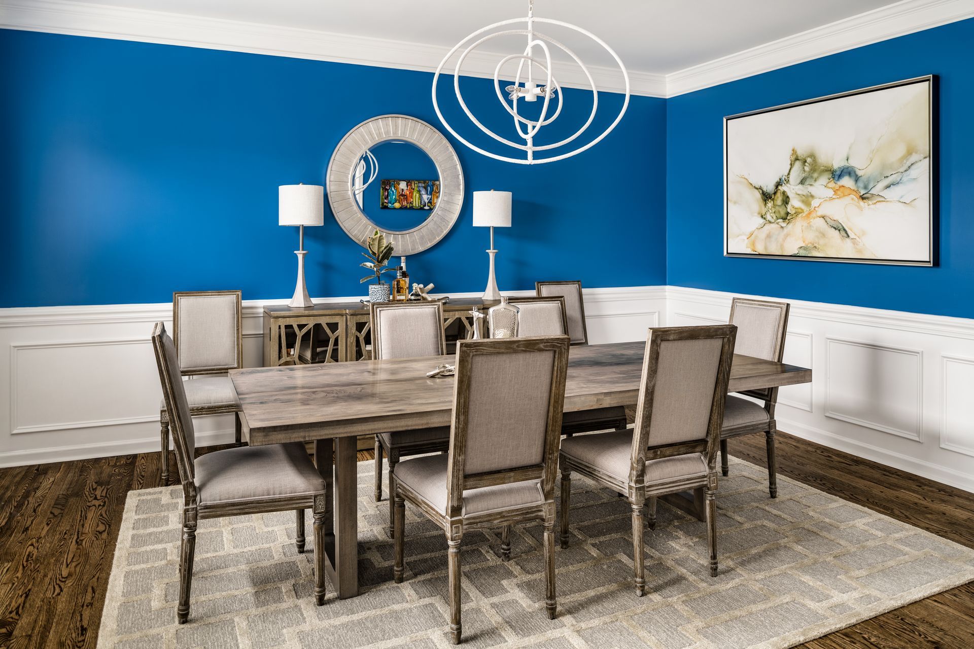 Dining room with blue walls, white trim, and a long wooden table set for guests.