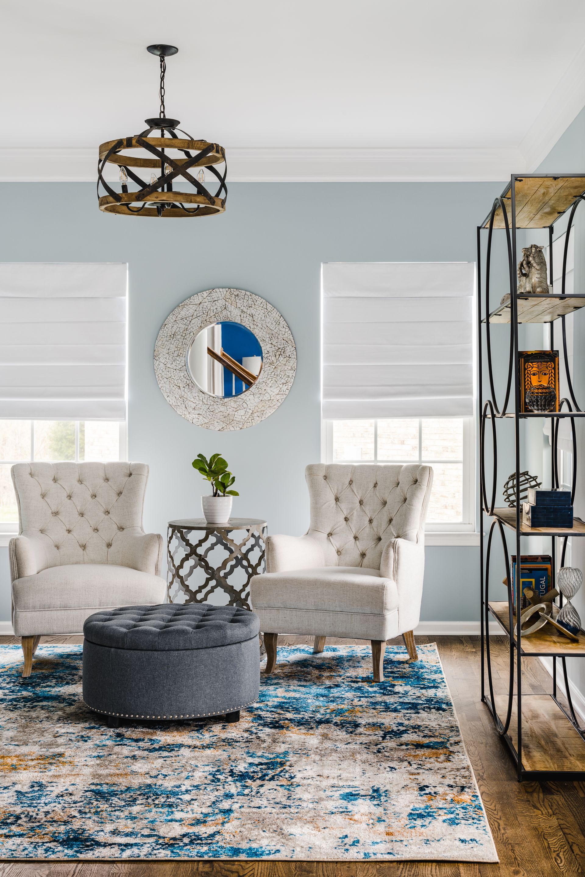 Living room with blue walls, two tufted armchairs, rug, and an ottoman.