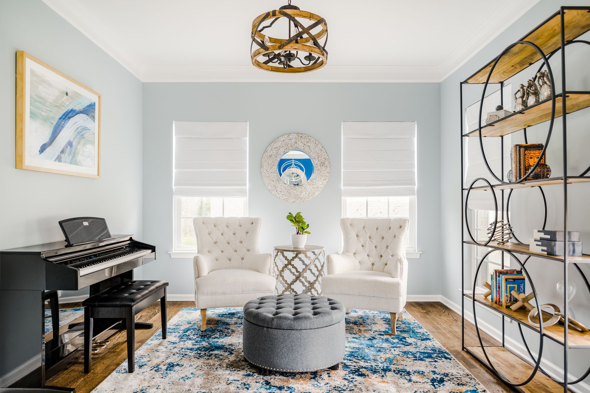 Blue-walled room with piano, two armchairs, and decorative shelving. Blue and white rug, and drum-shaped ottoman.