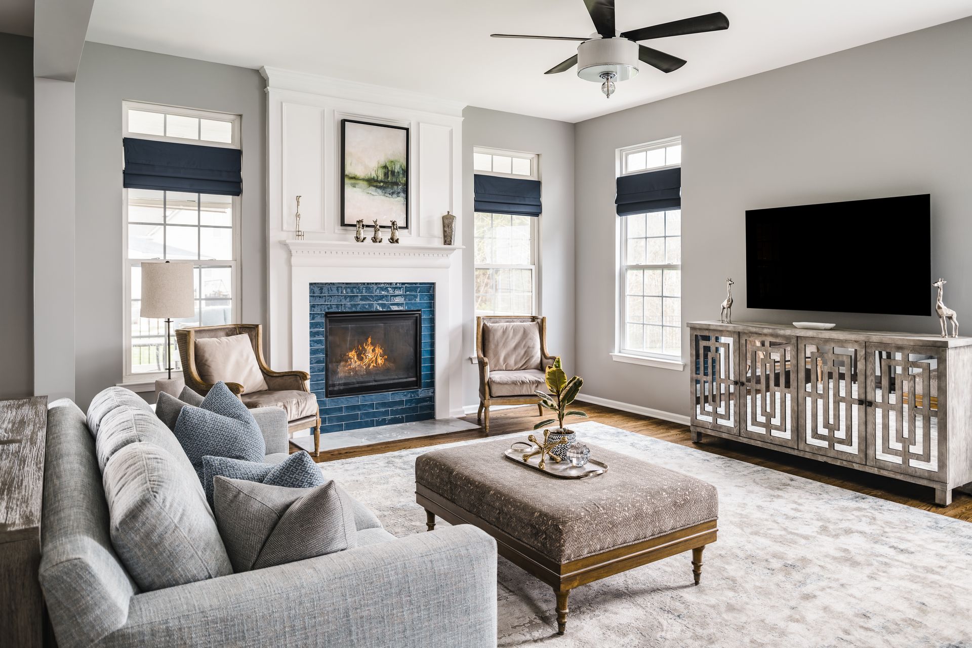 Living room with gray walls, a fireplace, and a large TV. Blue accents and a neutral rug.