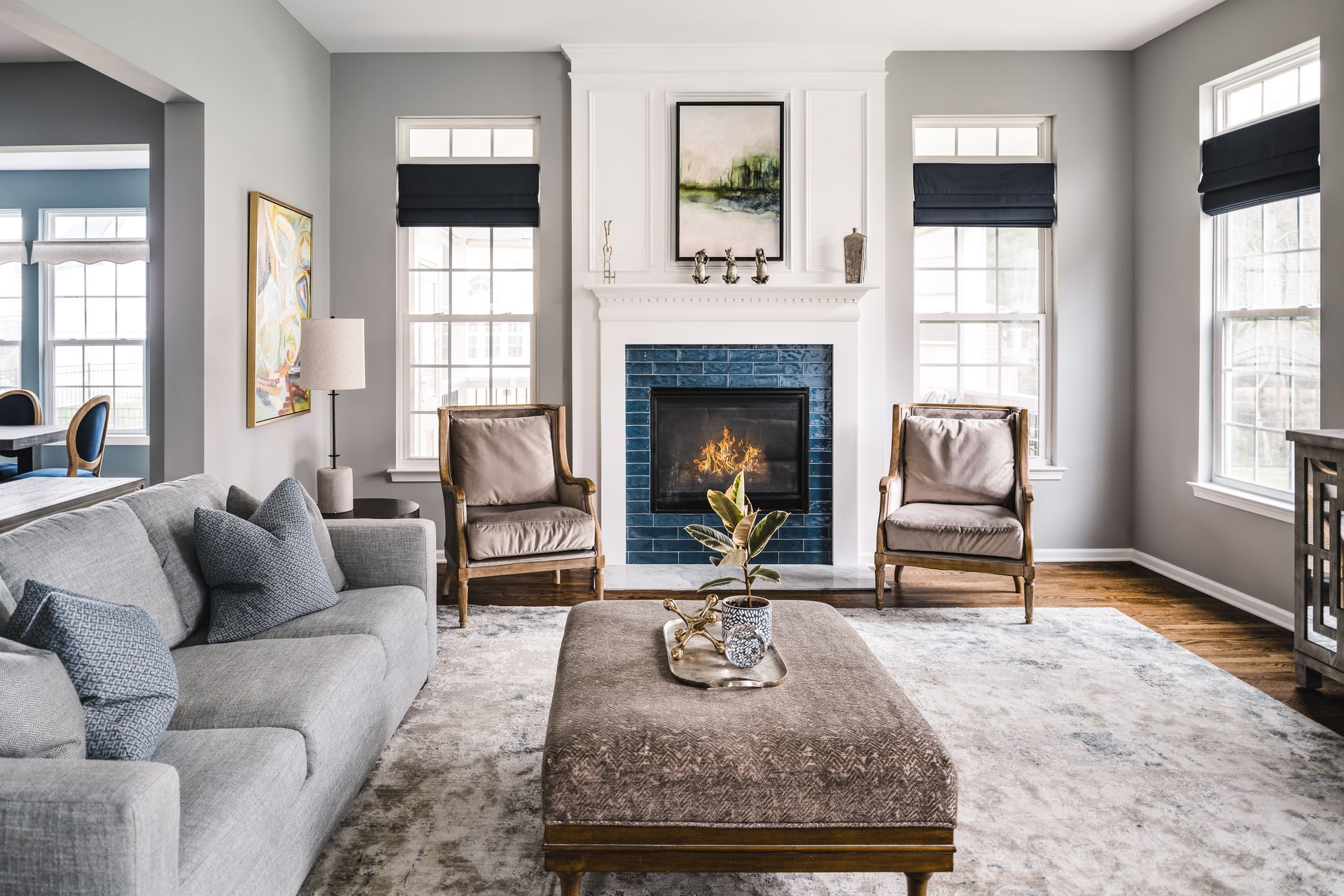 Living room with gray walls, fireplace, sofa, armchairs, and large ottoman.