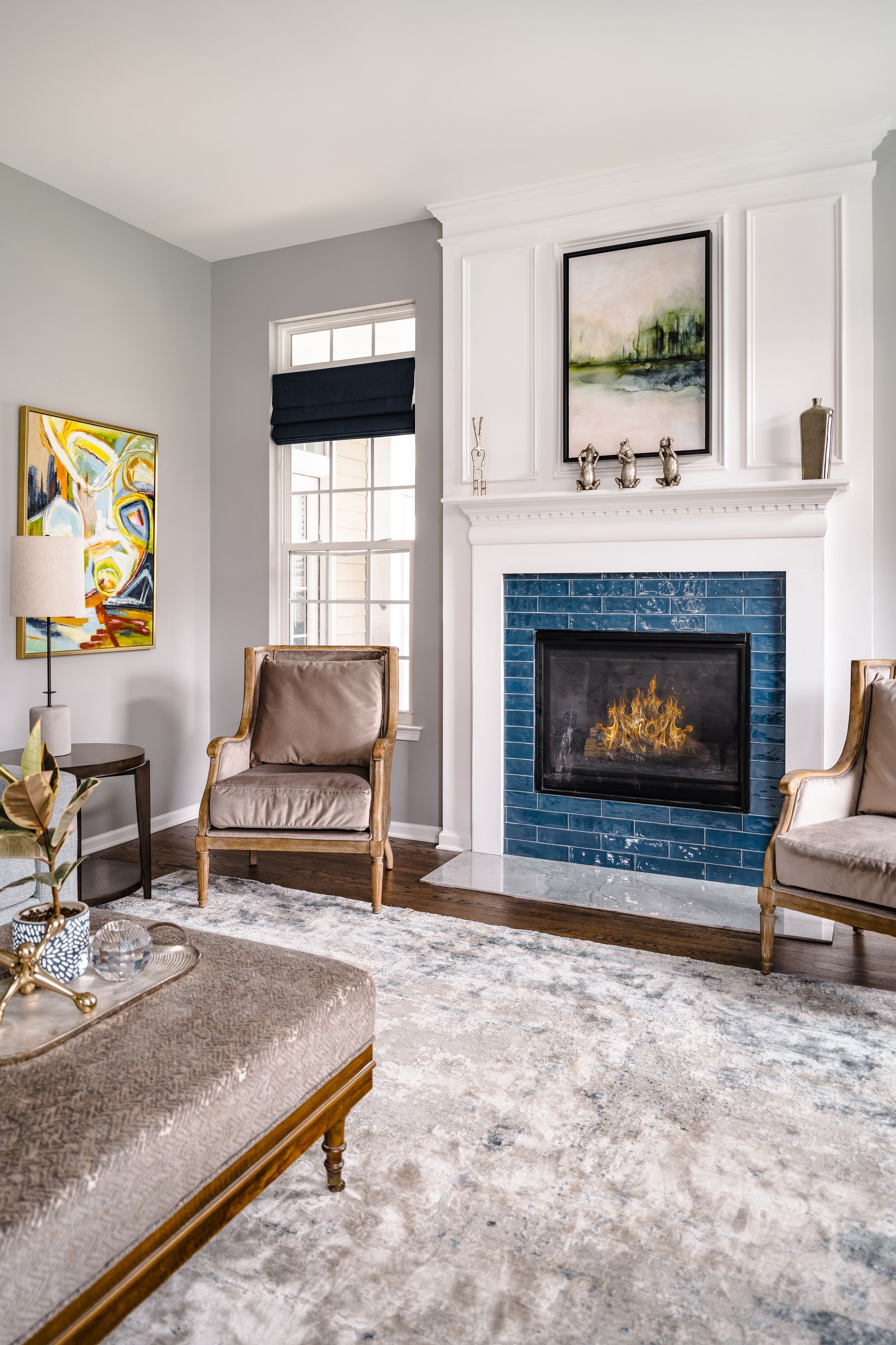 Living room with fireplace, two armchairs, and an ottoman on a patterned rug.