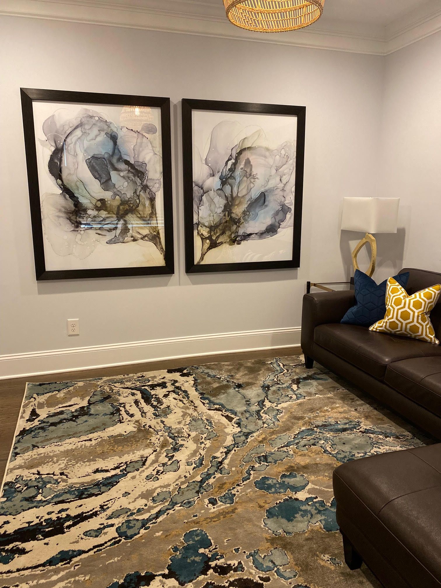 Living room with framed art, brown leather sofa, patterned rug, and ottoman.
