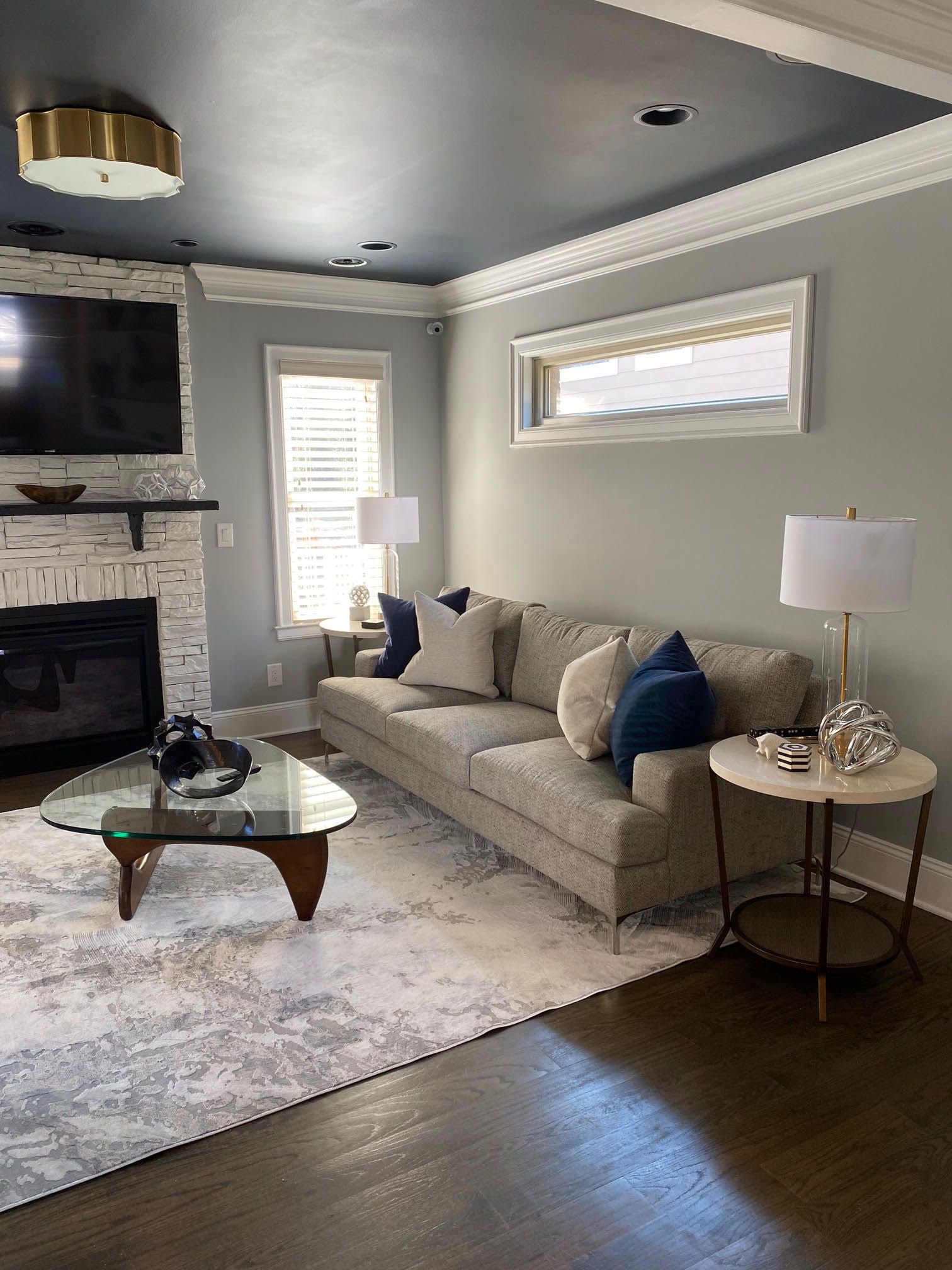 Living room with gray walls, light sofa, fireplace, and rug, with dark wood floor.