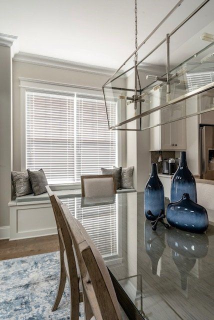 Dining room with a table, blue vases, a window seat, and modern chandelier.
