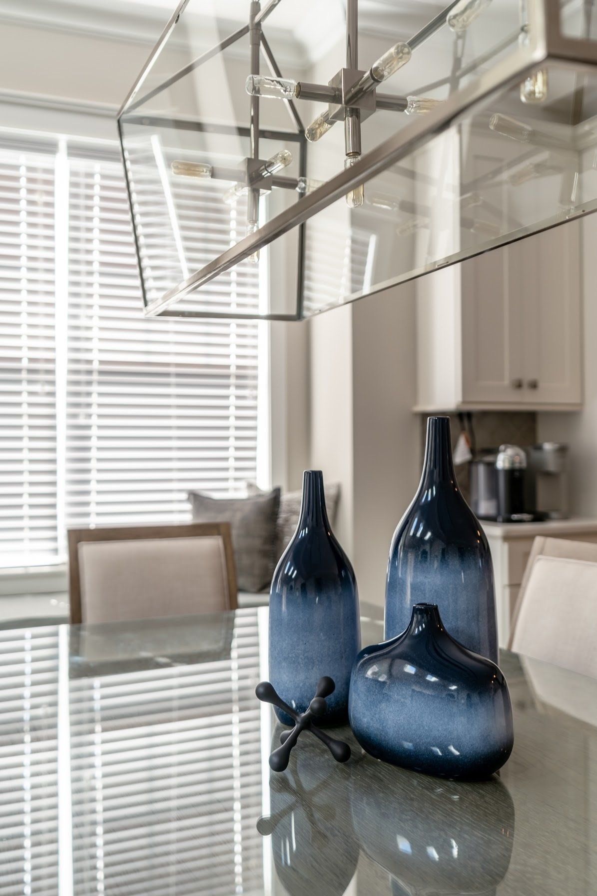 Blue vases and jack sculpture on a reflective surface with window and light fixture in the background.