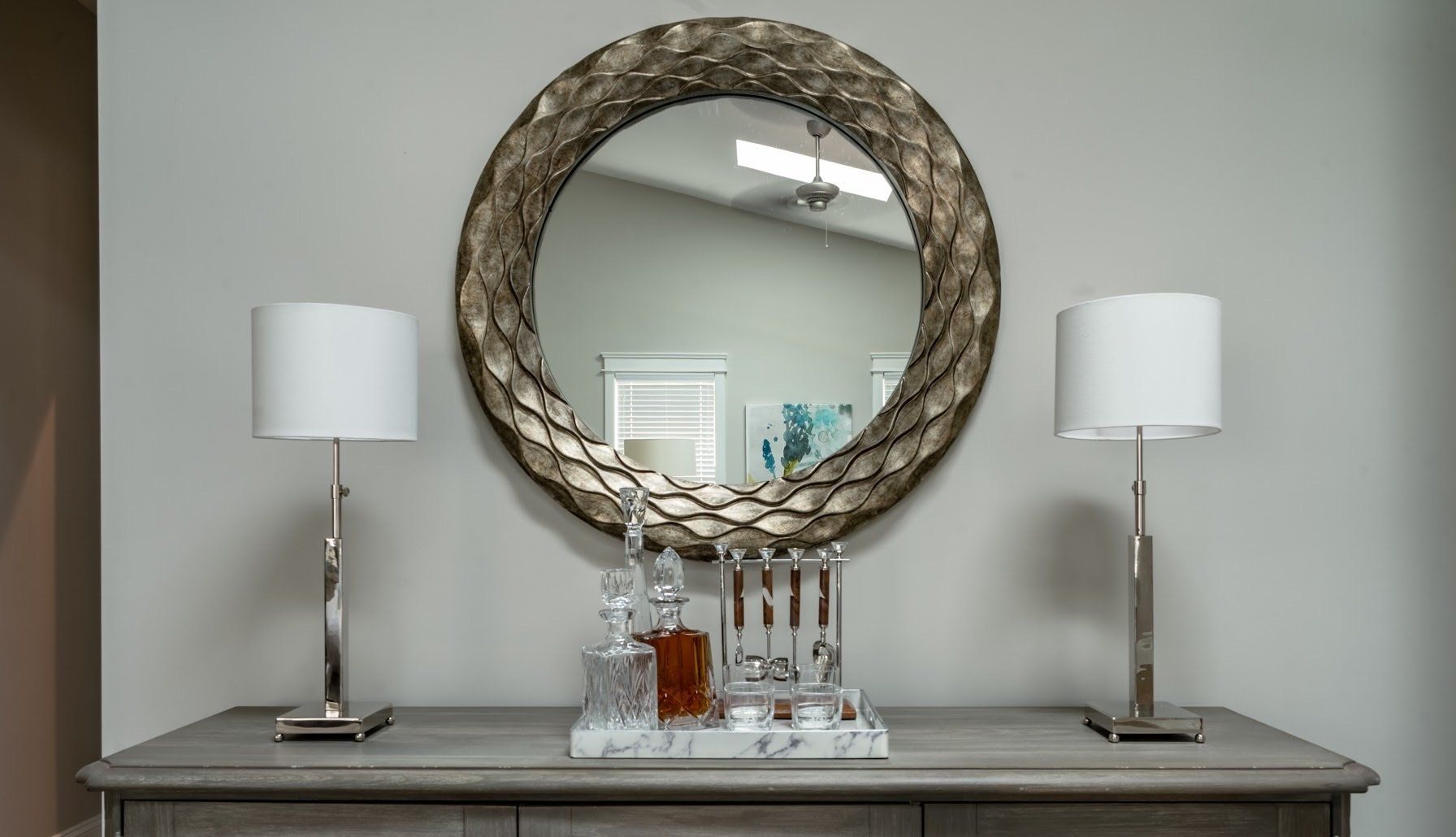 Gray console table with mirror, lamps, and bar setup.