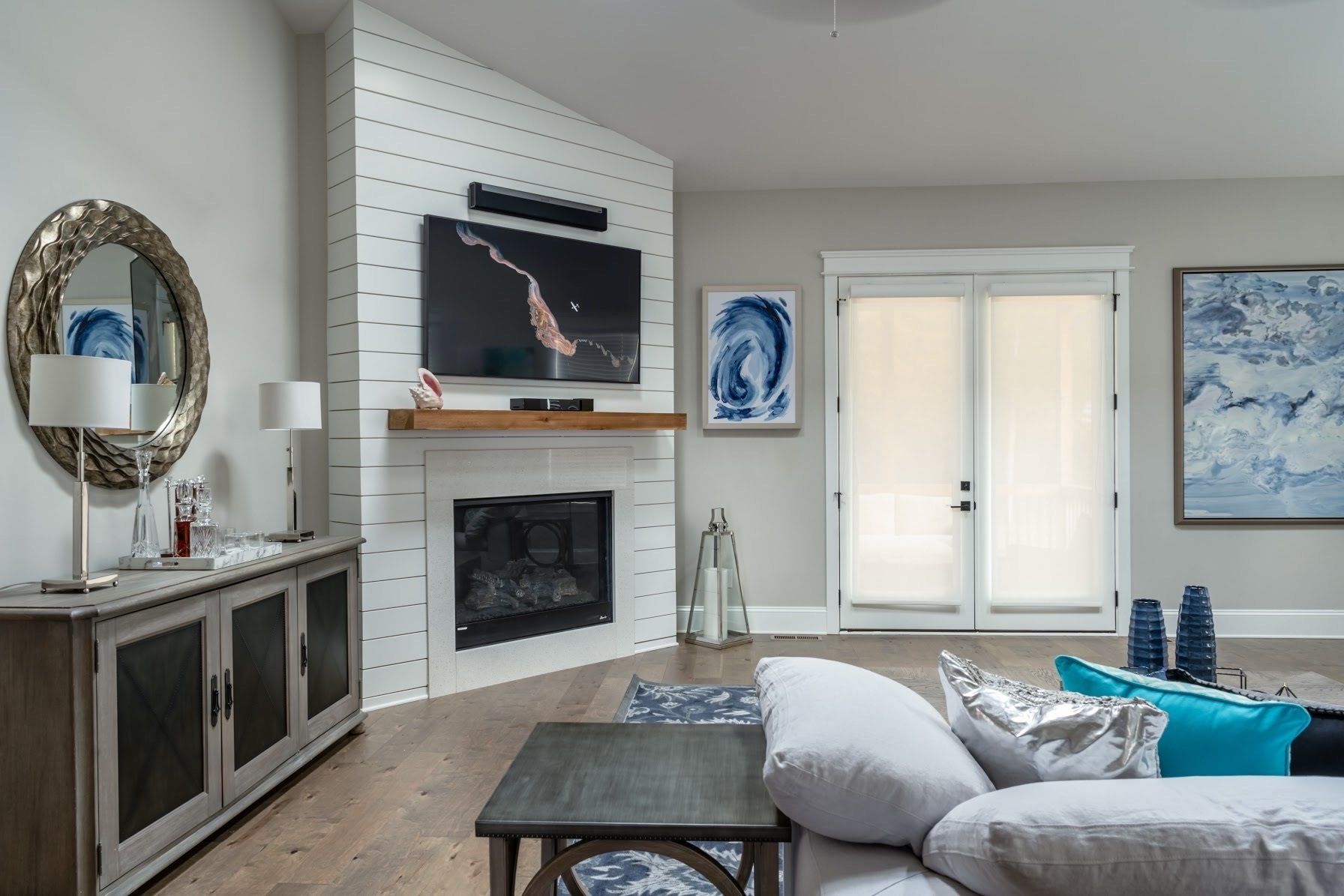 Living room with fireplace, TV, sofa, mirror, and light blue and gray decor.
