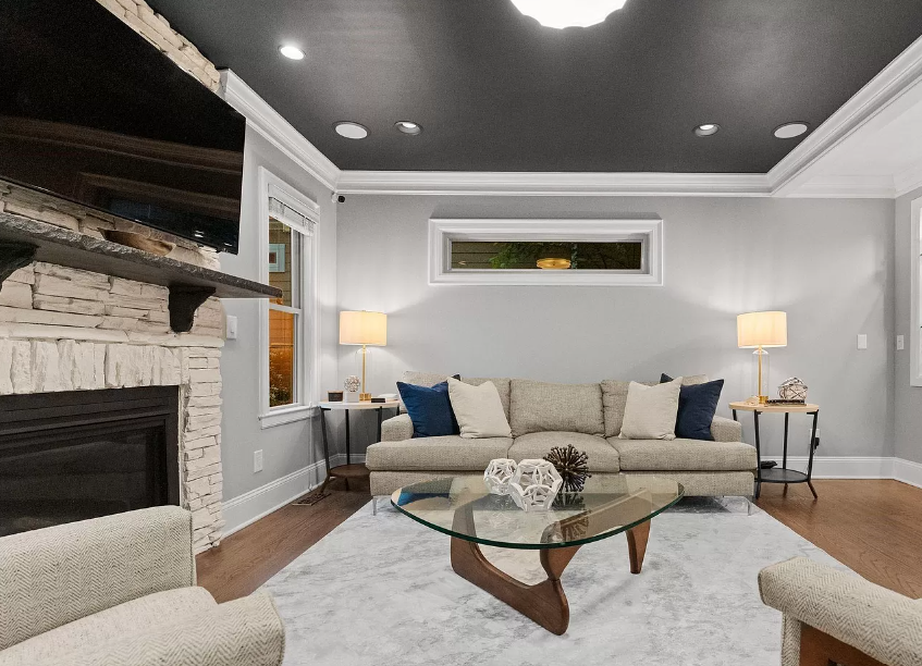 Living room with a fireplace, sofa, and glass coffee table; neutral colors, wood floor.