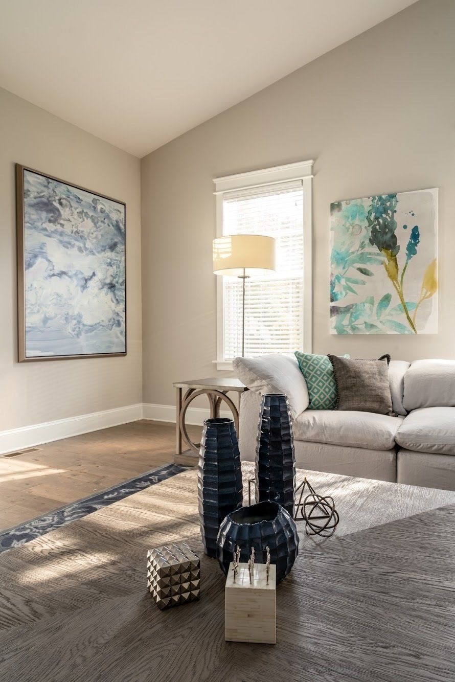 Living room with abstract art, sofa, vases, and natural light.