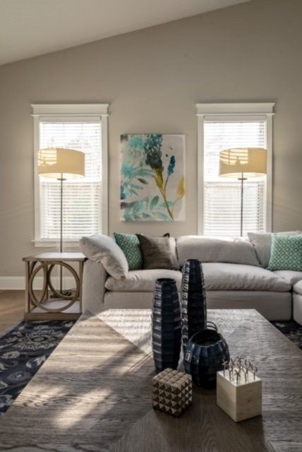 Living room with gray walls, white trim, sectional sofa, art, lamps, and a wood coffee table.
