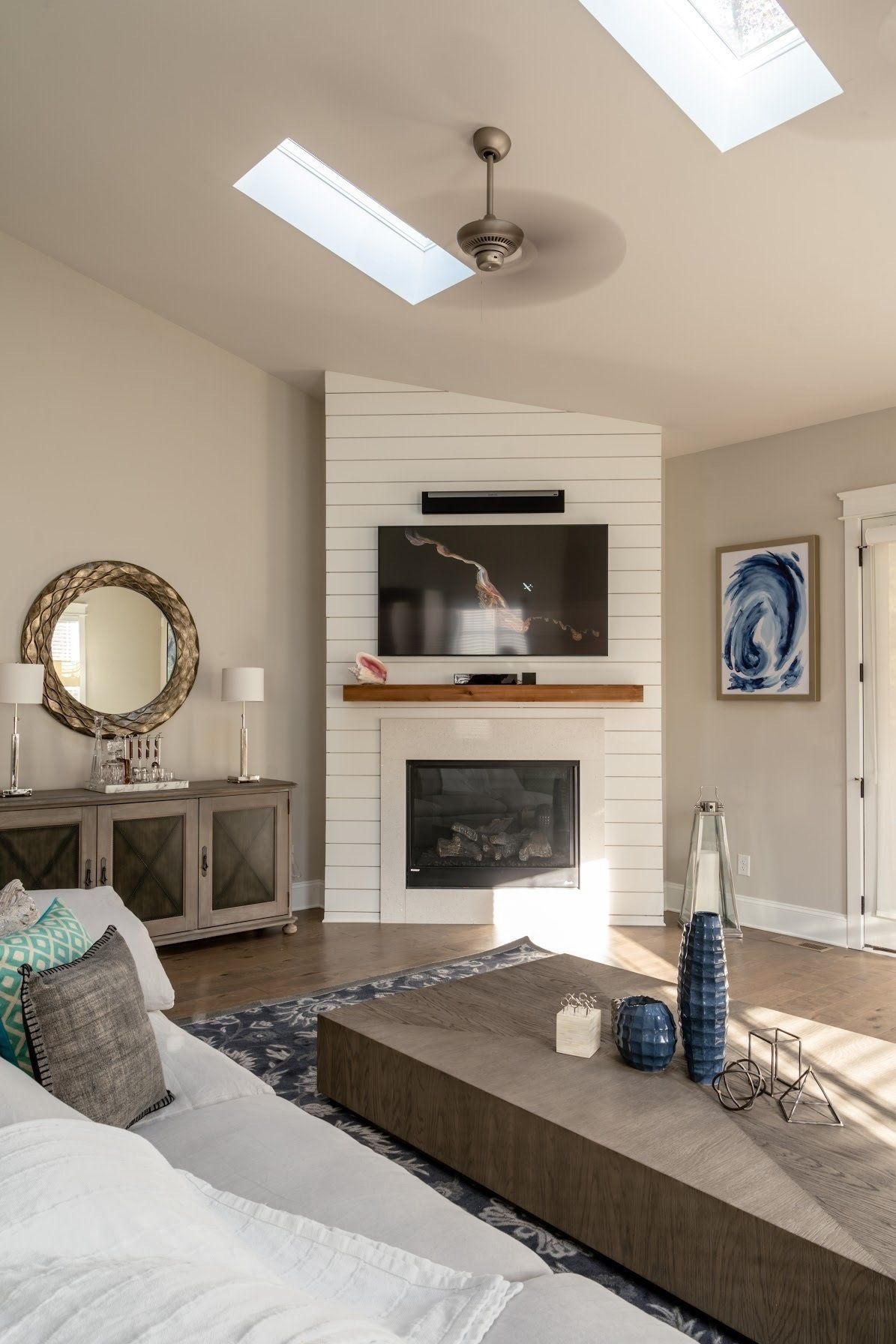 Living room with fireplace, TV, and sofa, featuring neutral colors, wooden accents, and natural light.