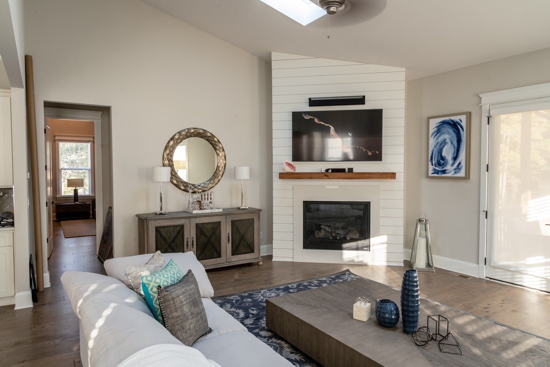 Living room with fireplace, TV, and couch. Neutral colors, wood floors, and decorative accents.
