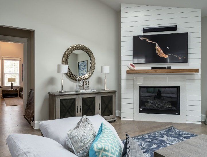Living room with fireplace, TV, mirror, and console table; light gray walls.