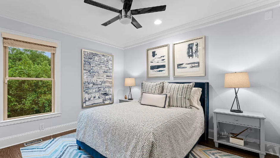 Bedroom with blue accents: bed, art, nightstands, and window overlooking trees.