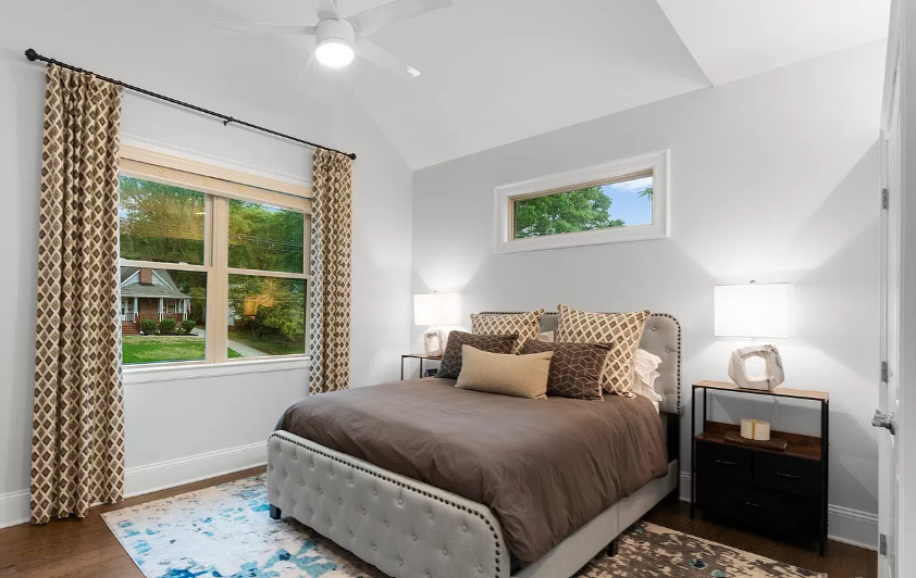 Bedroom with bed, nightstands, window with patterned drapes, and light-colored walls.