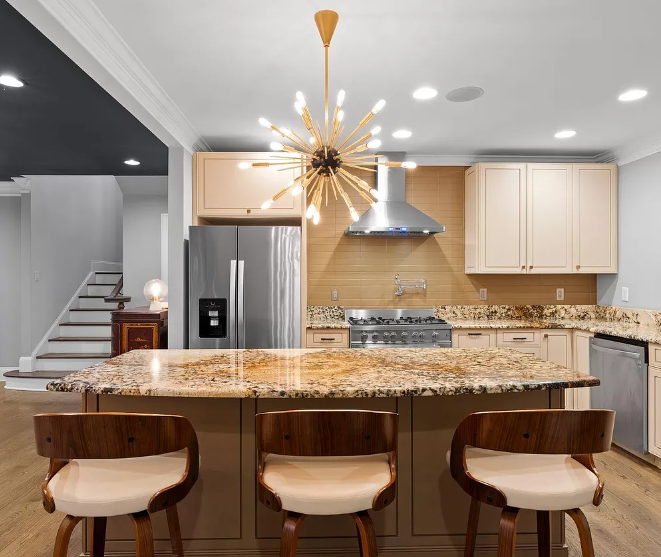 Kitchen with island, stainless steel appliances, pendant light, wood and granite. Three bar stools.
