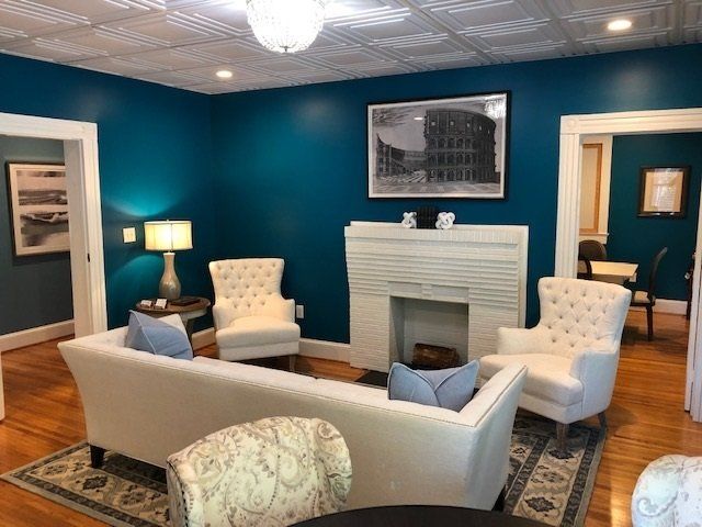 Living room with teal walls, white furniture, fireplace, and artwork.