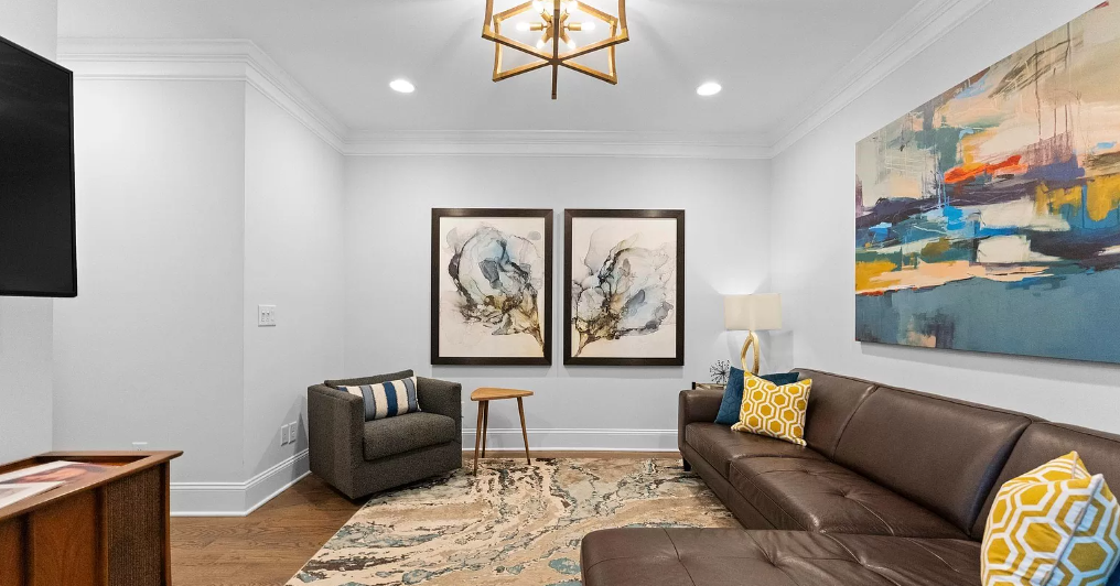 Living room with brown leather sofa, abstract art, and gray armchair.