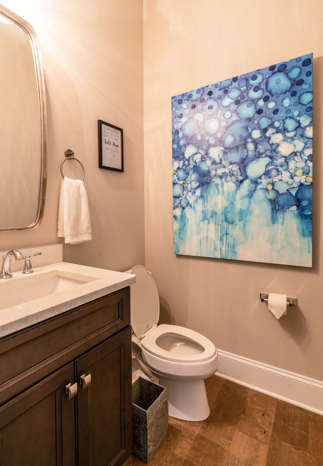 Powder room with artwork above the toilet and a dark wood vanity.