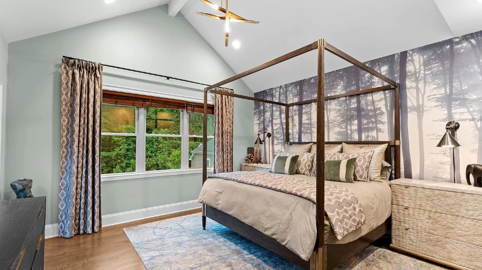 Bedroom with canopy bed, forest mural, window with curtains, and blue rug.