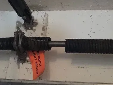 Garage door torsion spring with warning tag attached.