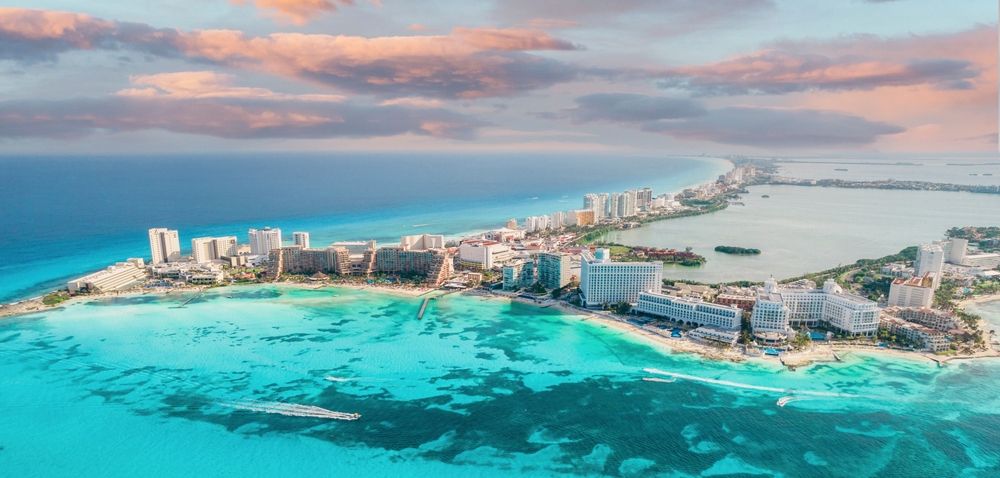 Aerial view of Cancun, Mexico, showing hotels along the coast and turquoise waters.