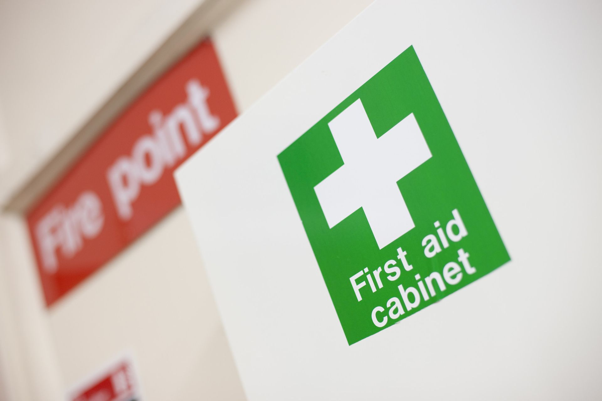 a first aid cabinet with a white cross on it and a fire point sign in the background